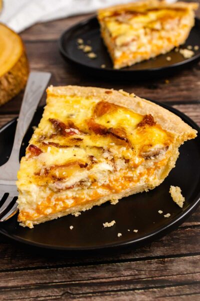 Sloce of Bacon Cheddar Quiche on a plate with a fork.