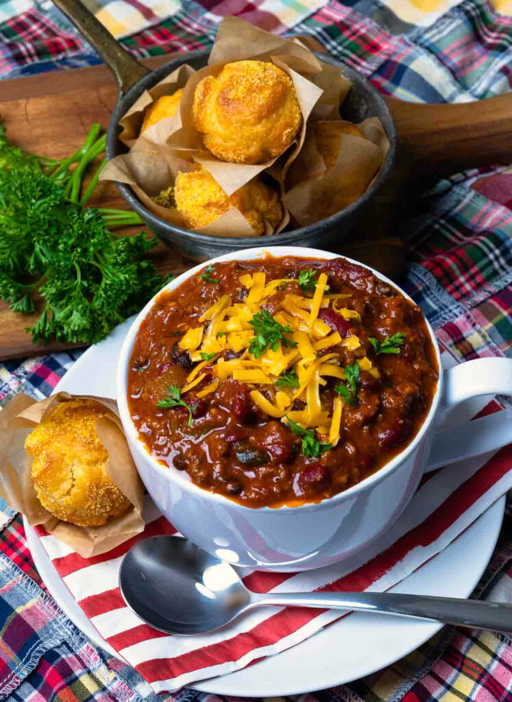 Award Winning Southern Soul Chili in a bowl topped with cheese and served with cornbread muffins.