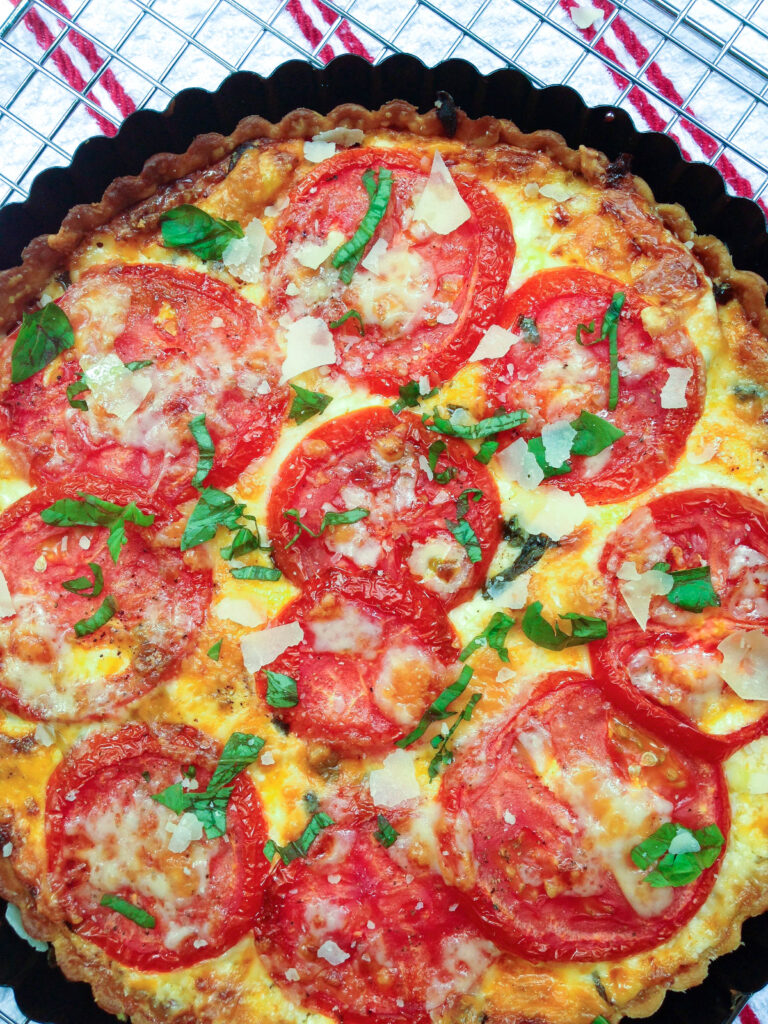 Southern Tomato Pie is a classic summertime dish. Layers of tomatoes, cheese, pesto, herbs and onions are baked in a flaky crust for a savory pie that's downright scrumptious.