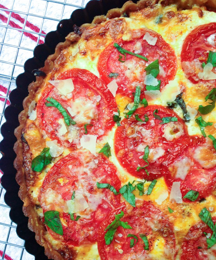 Southern Tomato Pie is a classic summertime dish. Layers of tomatoes, cheese, pesto, herbs and onions are baked in a flaky crust for a savory pie that's downright scrumptious.