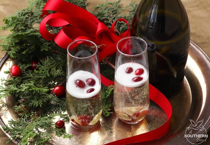 Make your holiday season extra bright with this signature cocktail! Mistletoe Mimosas, made with sparkling apple cider and Proscecco with chilled fruit is a great way to share a little holiday happiness.