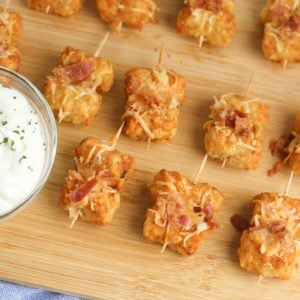 Tater Tots made into loaded little appetizer bites are a great appetizer or snack. Topped with cheese & bacon then dipped into creamy sour cream, they become a savory treat everyone will love.