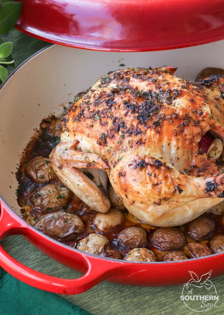 Herb butter with thyme, basil and oregano flavors a whole chicken roasted in the oven on a bed of new potatoes.