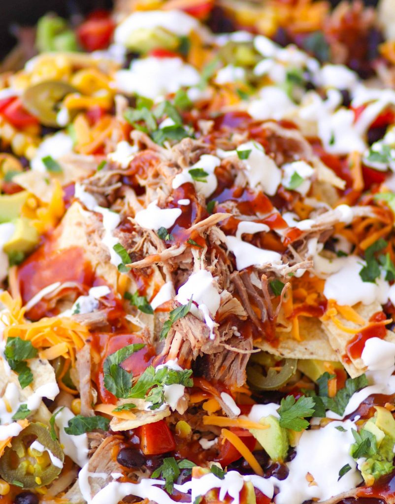 Pulled Pork cooked in the Instant Pot is tender and juice. It's then turned into nachos loaded with cheese, beans, corn, peppers, avocado, BBQ sauce and sour cream for a dish that is out of this world!