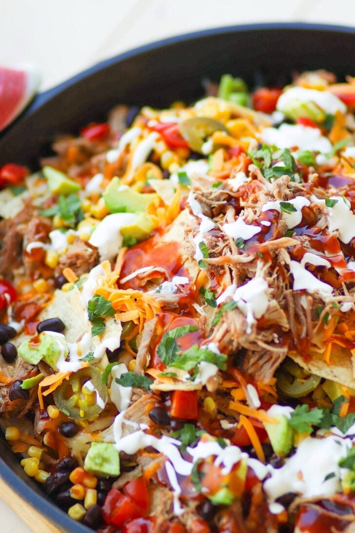 Pulled Pork cooked in the Instant Pot is tender and juice. It's then turned into nachos loaded with cheese, beans, corn, peppers, avocado, BBQ sauce and sour cream for a dish that is out of this world!