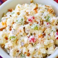 Ambrosia salad made with oranges, cherries, pineapple and marshmallows is tossed in a light fluffy mixture of fresh whipped cream with a touch of sour cream for extra flavor.