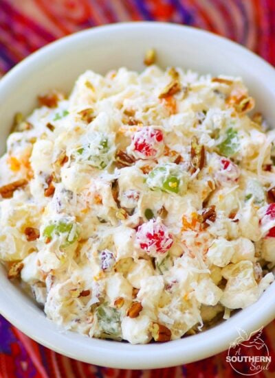Ambrosia salad made with oranges, cherries, pineapple and marshmallows is tossed in a light fluffy mixture of fresh whipped cream with a touch of sour cream for extra flavor.