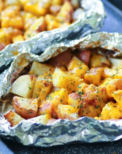 Red potatoes flavored with ranch seasoning then cooked on the grill in foil packets are loaded with cheese for a side dish that is perfect for any cookout or BBQ!