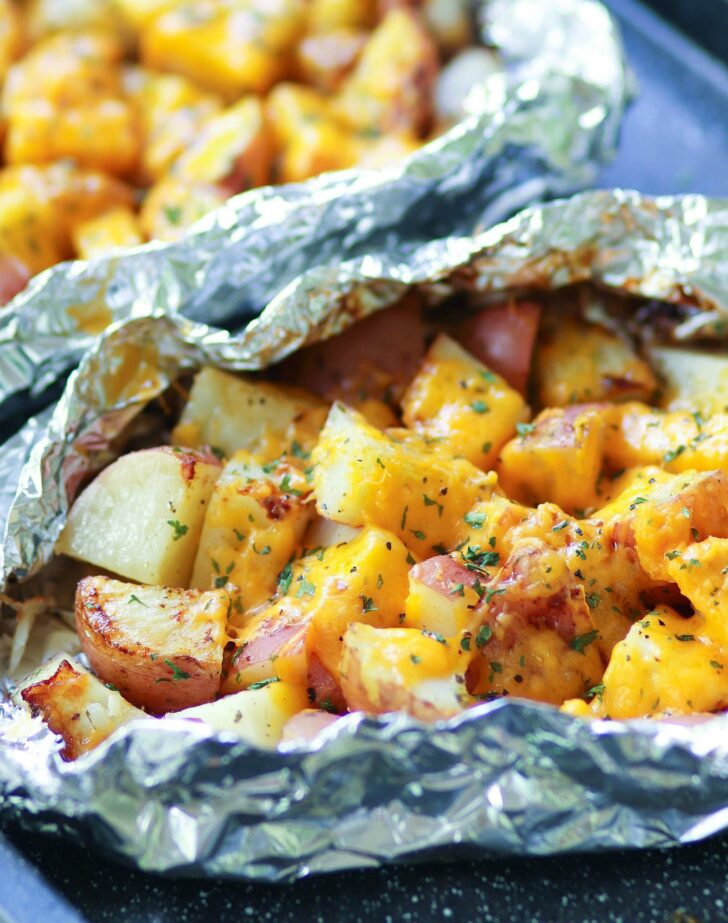 Red potatoes flavored with ranch seasoning then cooked on the grill in foil packets are loaded with cheese for a side dish that is perfect for any cookout or BBQ!