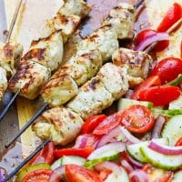 Grilled Chicken Souvlaki Skewers are juicy and tender. Make with lemon juice, oregano, garlic, salt and pepper. Add in a chopped salad with tomatoes, onions and cucumbers and you've got a meal your friends and family will love!