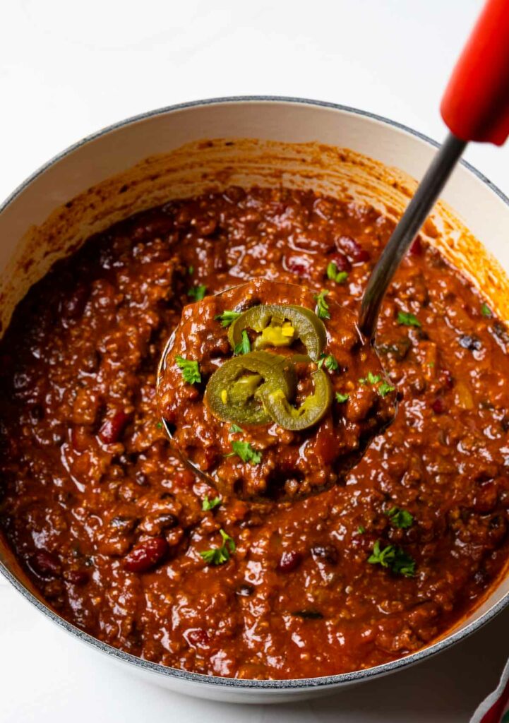 Southern Soul Award Winning Chili in a stock pot with ladle and jalapeno peppers.