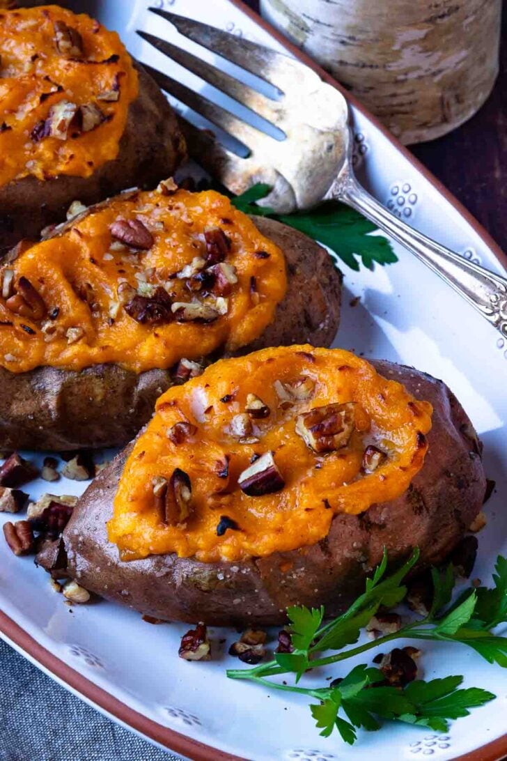 Twice baked sweet potatoes with toasted pecans on a platter with serving fork.