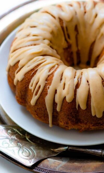 Buttermilk Pound Cake with brown butter icing on a plate with a silver cake cutter.
