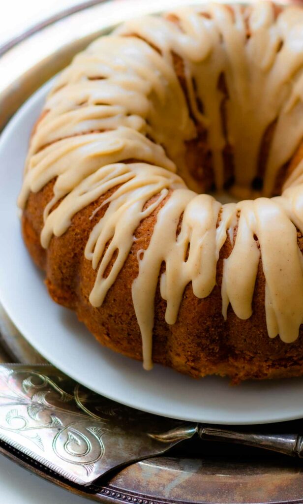 Buttermilk Pound Cake with brown butter icing on a plate with a silver cake cutter.
