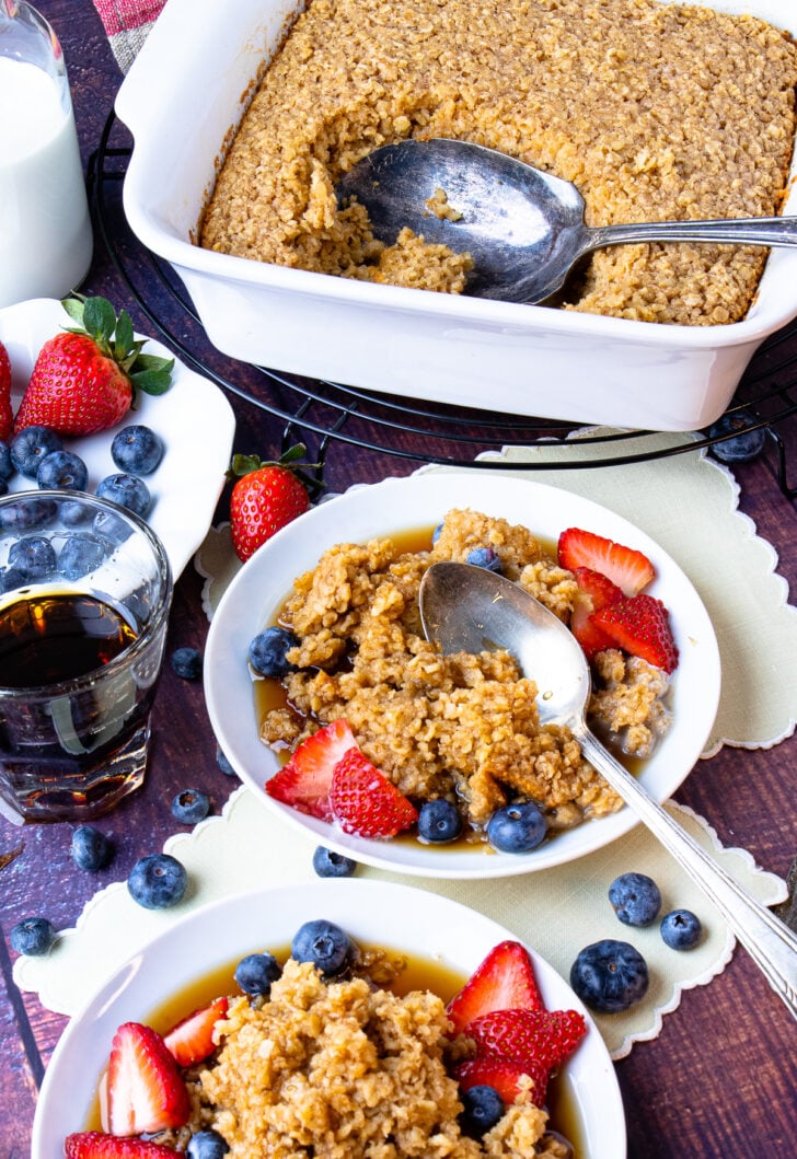 Baked Oatmeal on plates with maple syrup, blueberries and strawberries.
