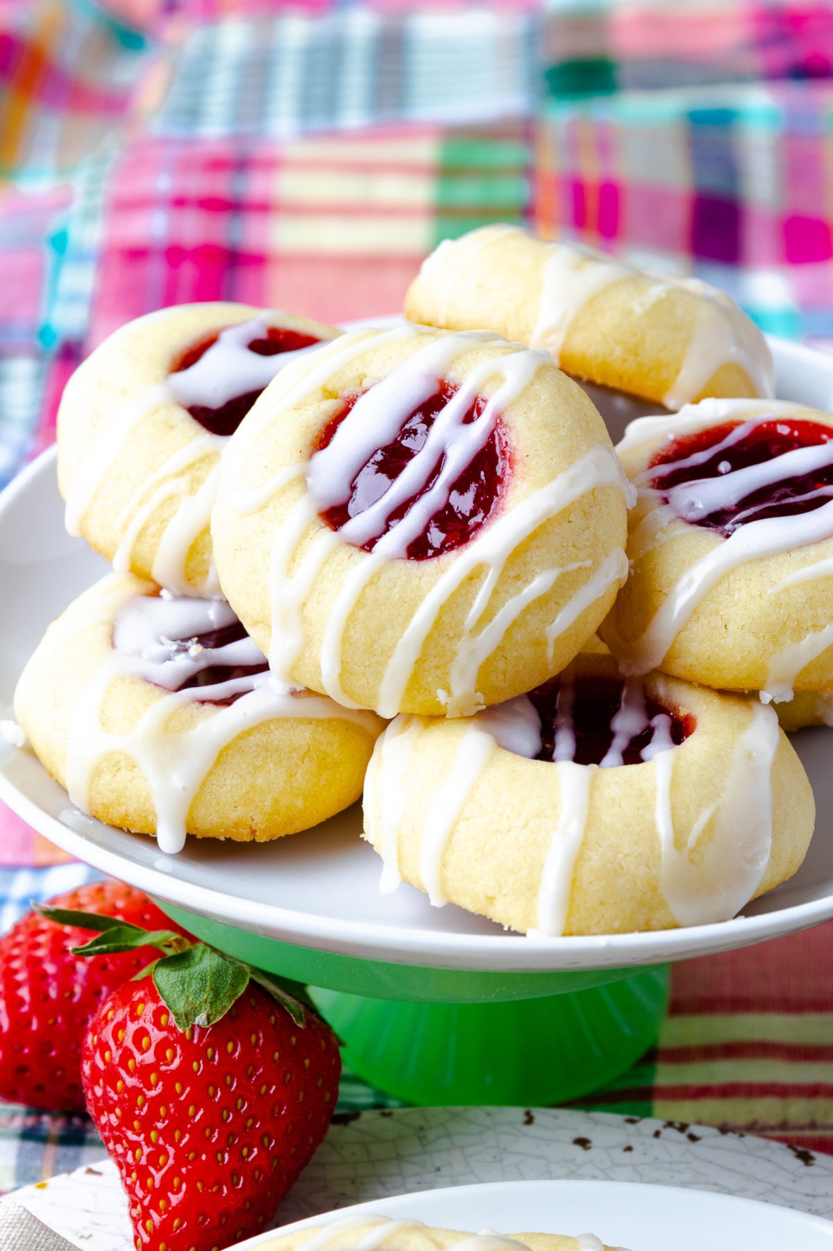 Jam Thumbprint Cookies on a white plate with stawberries.