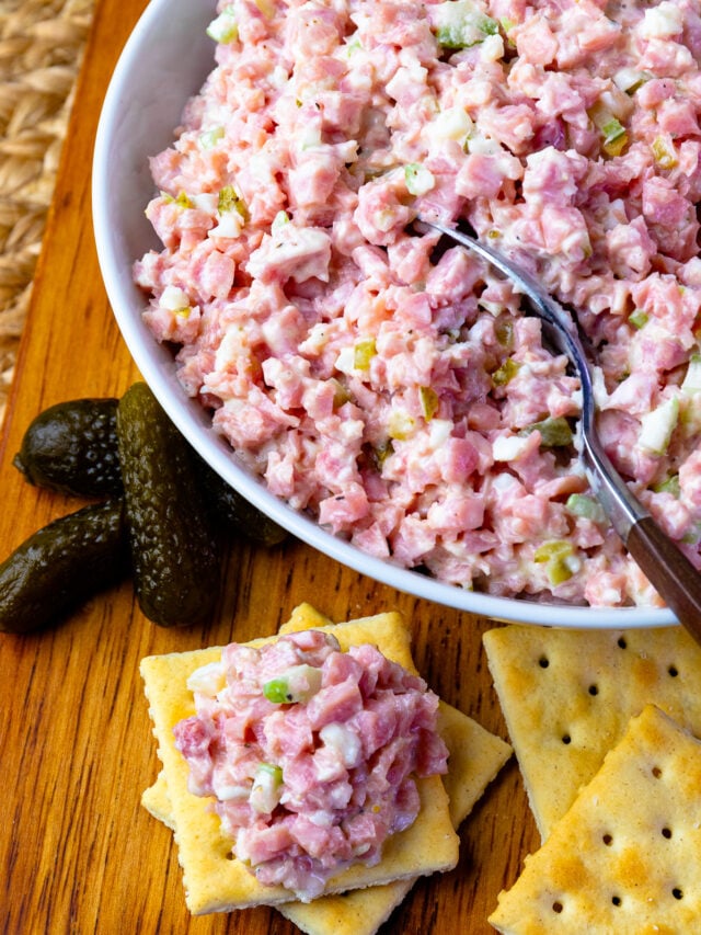 Ham Salad in a bowl with a spoon and pickles and crackers