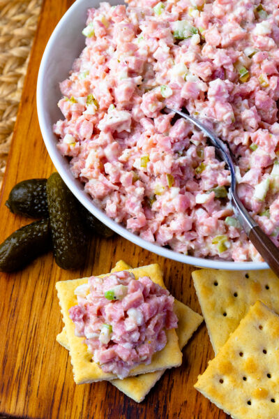 Ham Salad in a bowl with a spoon and pickles and crackers