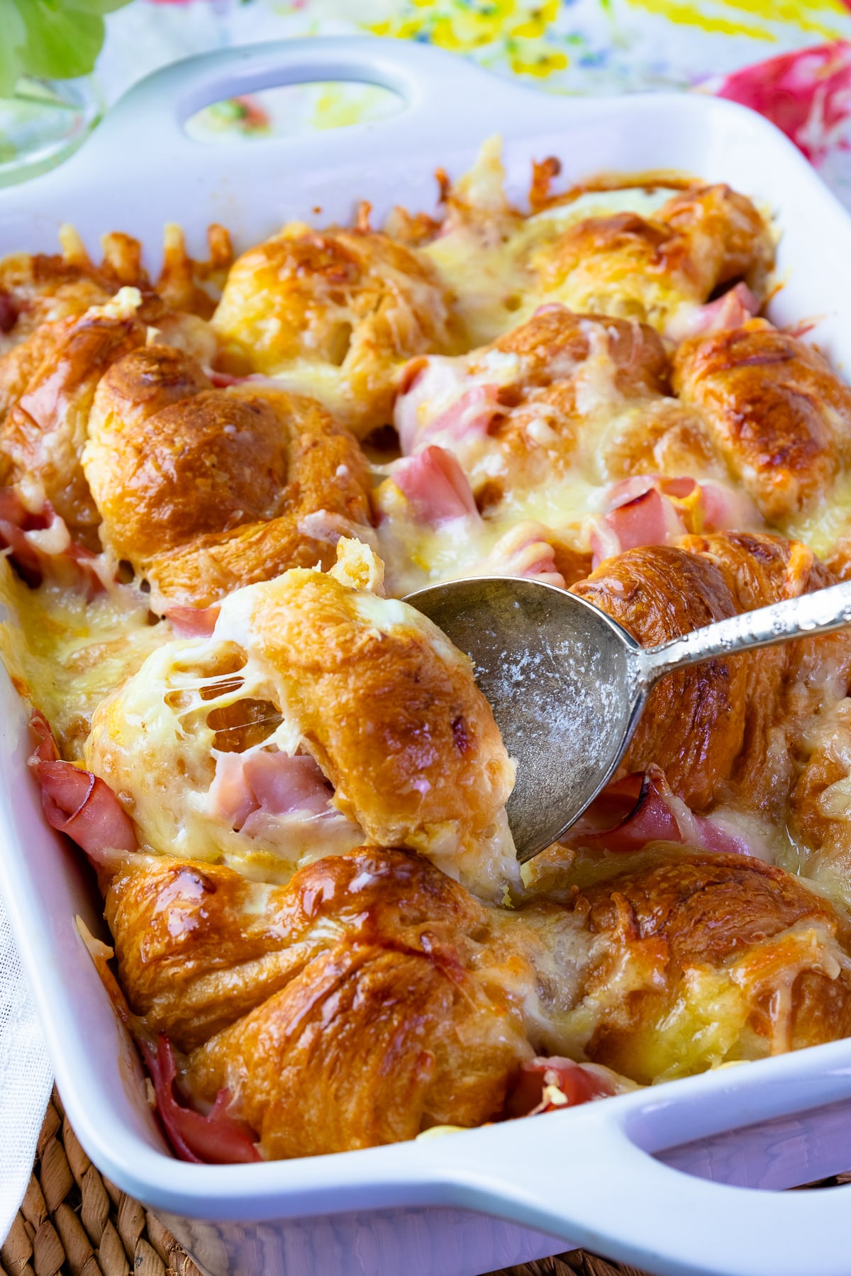 Ham and Cheese Croissant Breakfast Casserole with a spoon being served.