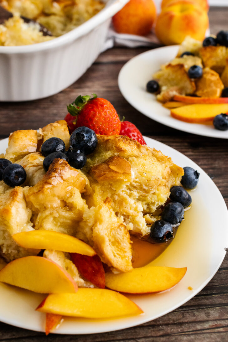 French Toast Bread Pudding on a plate with peaches and berries.
