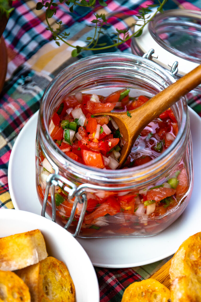 Tomato Relish in a jar with a wooden spoon for serving.