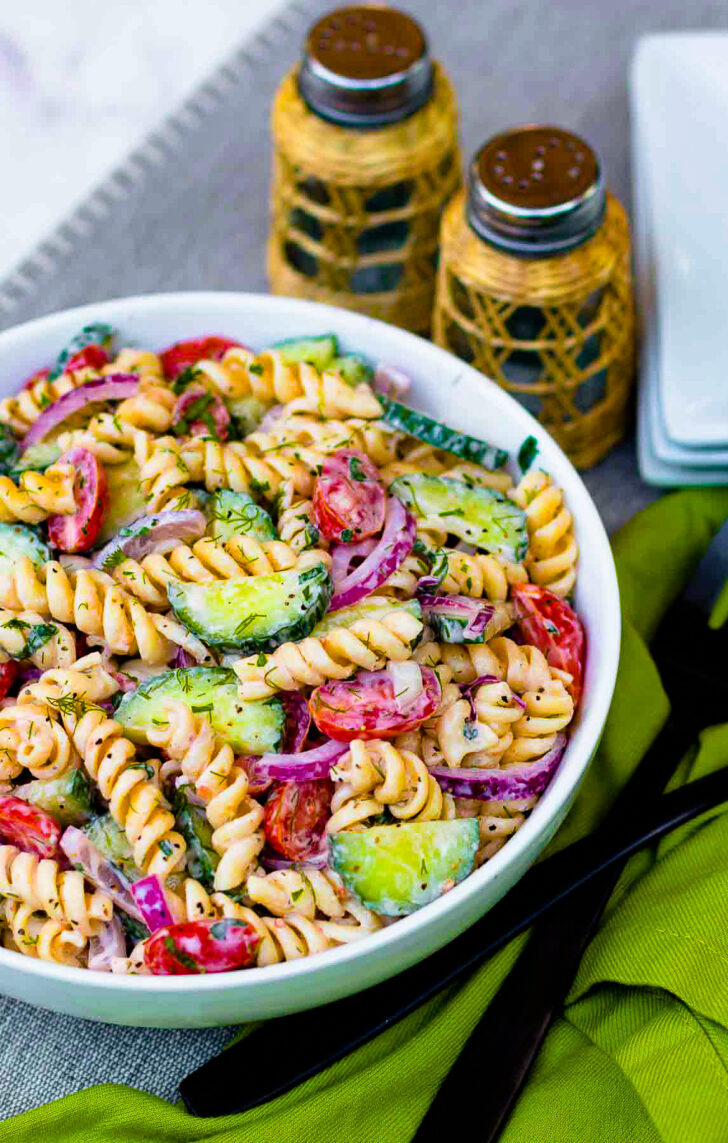 Creamy Tomato Cucumber Pasta Salad made with a simple dressing with fresh herbs and red onions.