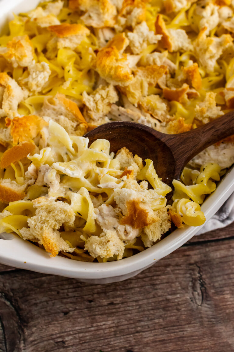 Creamy Chicken Casserole in a white casserole dish with a wooden spoon for serving.