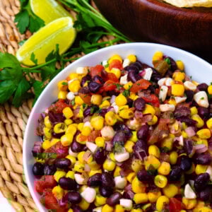 Balck Bean and Corn Salsa in a white bowl with limes for garnish.