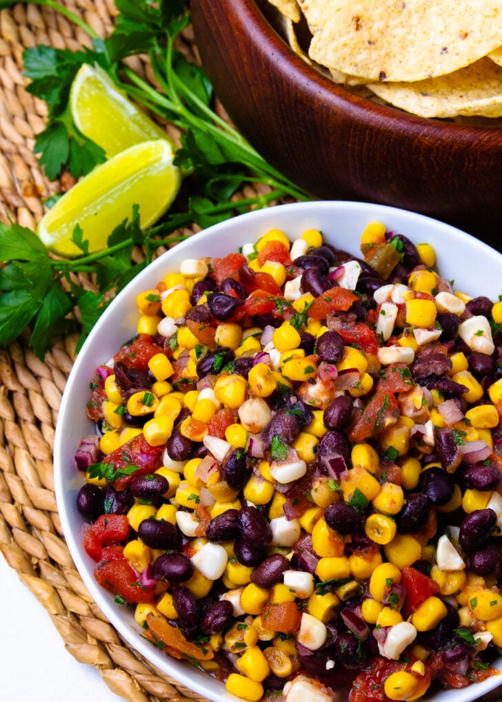Balck Bean and Corn Salsa in a white bowl with limes for garnish.