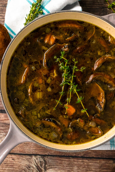 Gray stock pot with mushroom soup and fresh thyme.