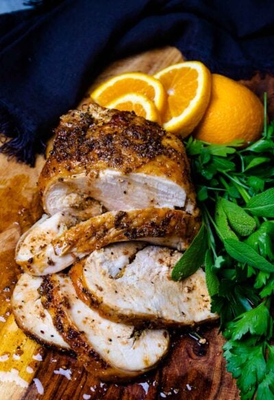 Air-Fryer Turkey Breast on a cutting board with herbs and oranges