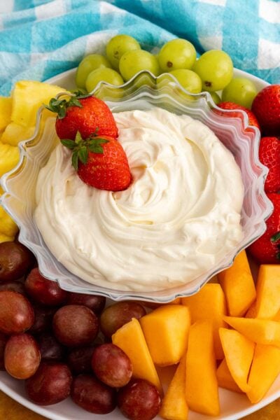 Strawberries in a bowl of 3-ingredient fruit dip surrounded with fresh fruit.