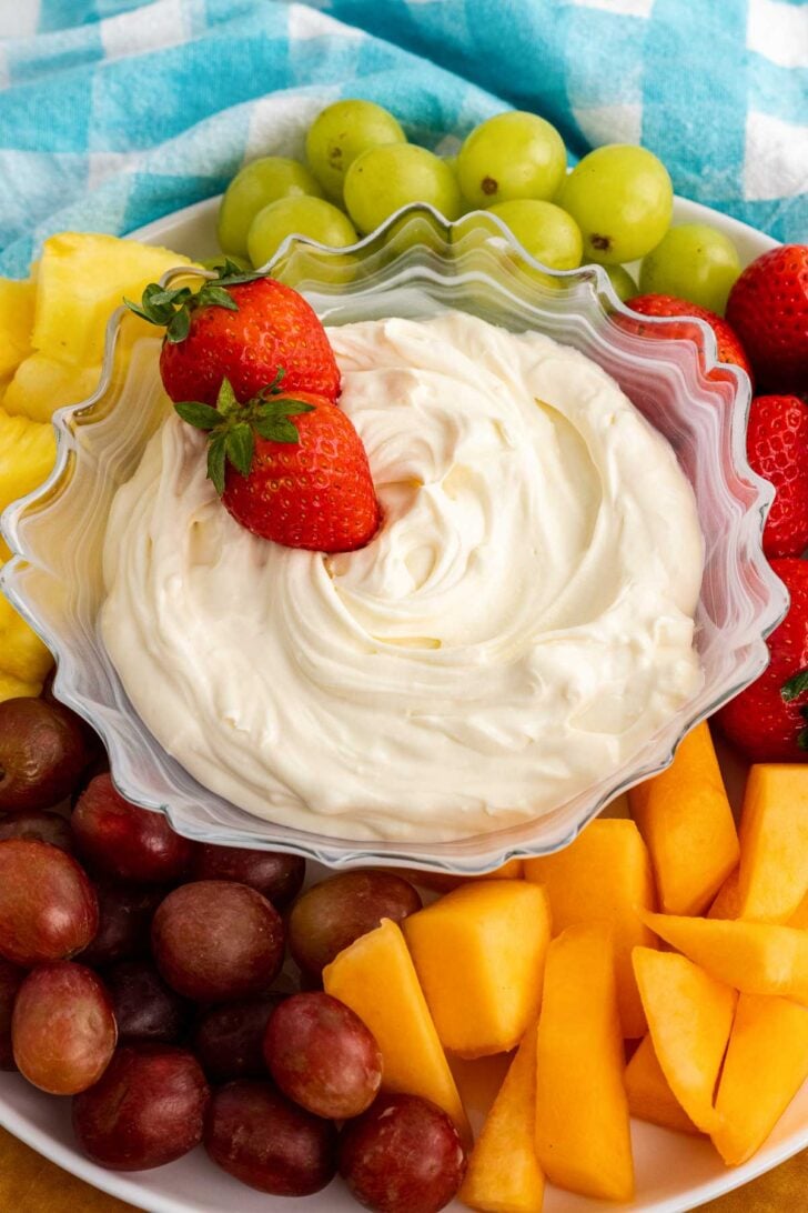 Strawberries in a bowl of 3-ingredient fruit dip surrounded with fresh fruit.
