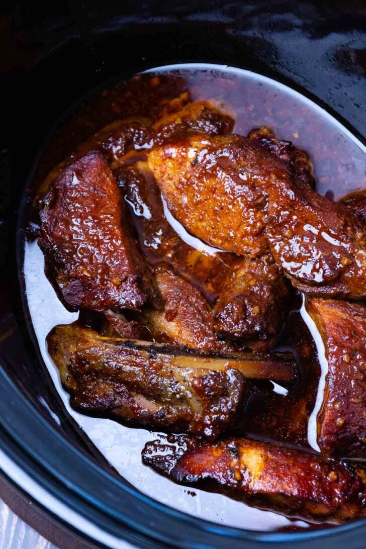 Pot of country style pork ribs cooked in a flavorful sauce in the crock pot.
