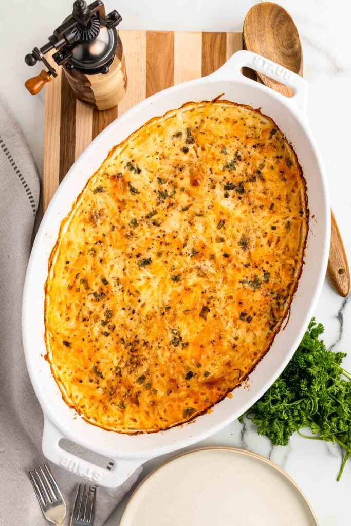 Baked hash brown casserole in a white baking dish.