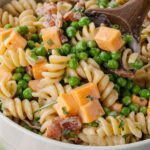 Bacon ranch pasta salad being tossed with a wooden spoon.