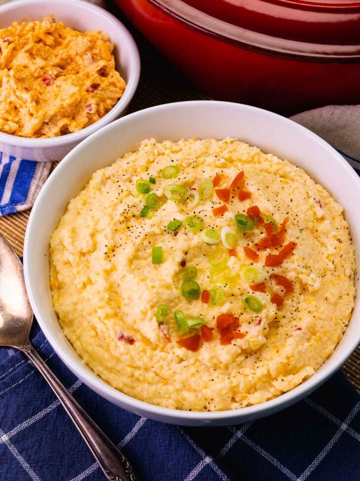 Big bowl of Pimento Cheese Grits topped with pimentos and sliced green onions.