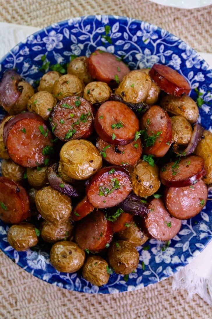 Beautiful blue plate loaded with Air Fryer Sausage And Potatoes sprinkled with parsley.