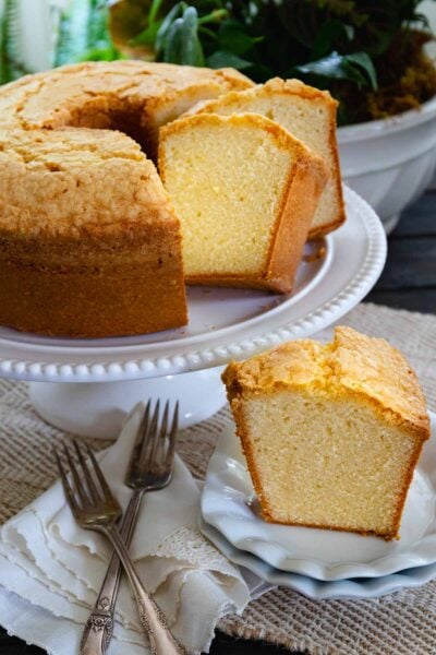 Slice of Million Dollar Pound Cake on a white plate along with sliced of cake served for dessert.