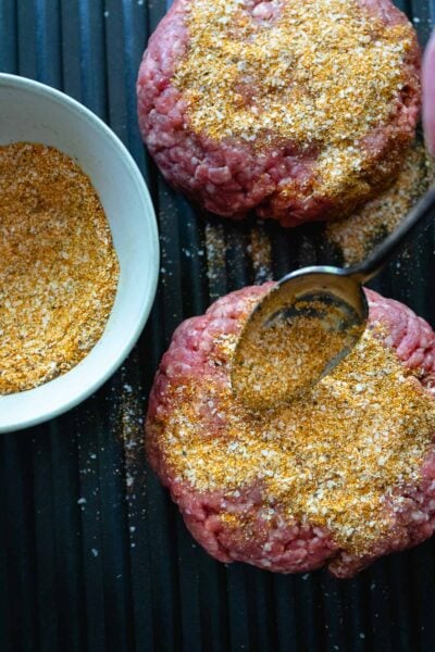 Homemade burger seasoning sprinkled on hamburger patties ready to cook.