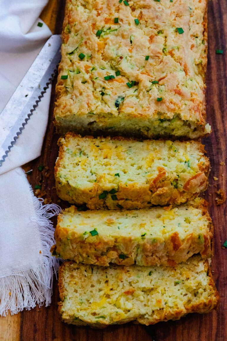 Loaf of delicious baked zucchini cheese bread, sliced on a cutting board served for dinner.