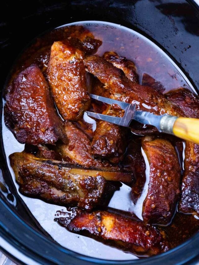 Slow cooker with glazed country ribs and fork, cropped cp country ribs fork 19 in white ceramic dish with caramelized sauce