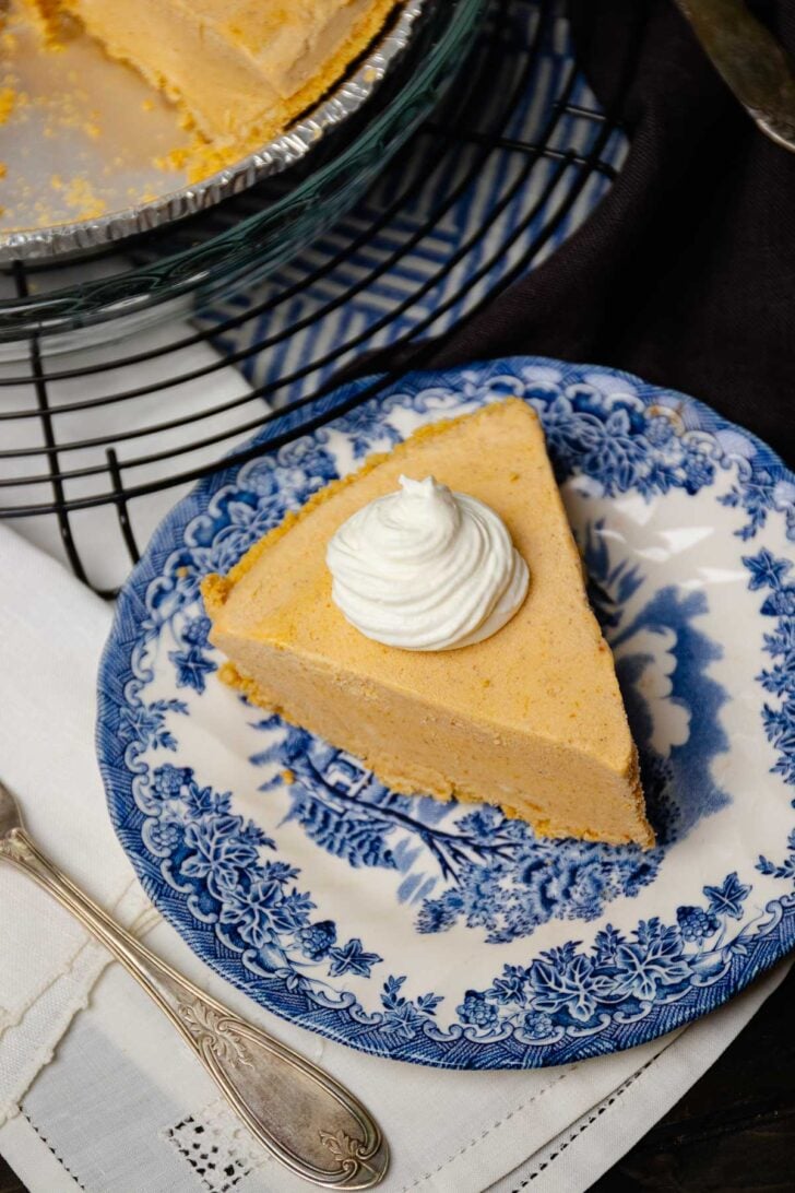 Slice of Creamy Pumpkin Icebox Pie with whipped cream served for dessert on a blue and white plate.
