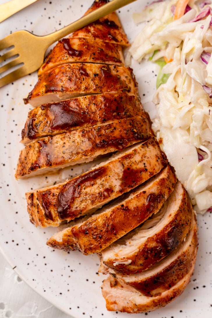 Tender, and juicy oven baked chicken with a rich BBQ sauce with all the flavors you love from summer grilling is easy to make and the perfect weeknight meal.