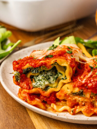 Spinach and cheese roll ups topped with tomato sauce and baked with a cheese topping is a twist on traditional lasagna that is so easy to make for a family meal.