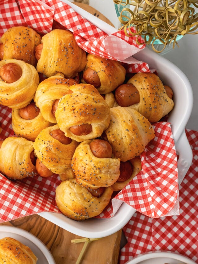 Crescent roll pigs in a blanket in a serving dish and small places served for as an appetizer with toothpicks.