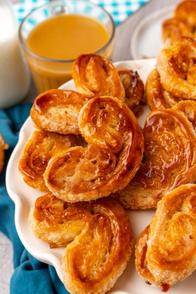 Classic Palmiers with a dashed of cinnamon baked until golden brown served on a white plate with a latte.