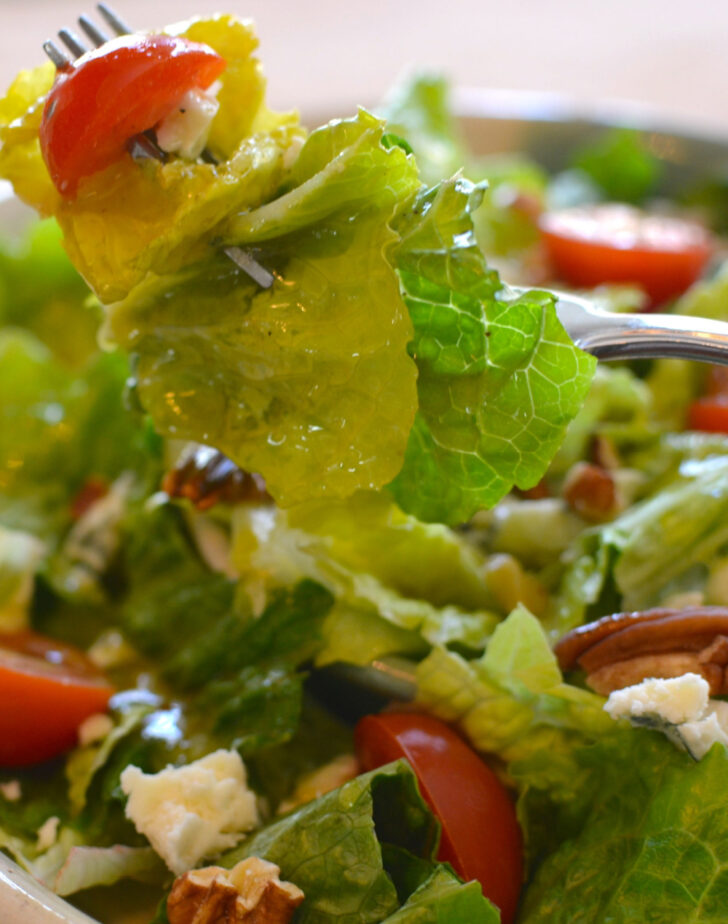 Fresh green salad and tomato on a fork.
