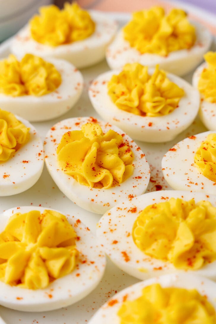 Stuffed deviled eggs on a white plate, sprinkled with paprika.