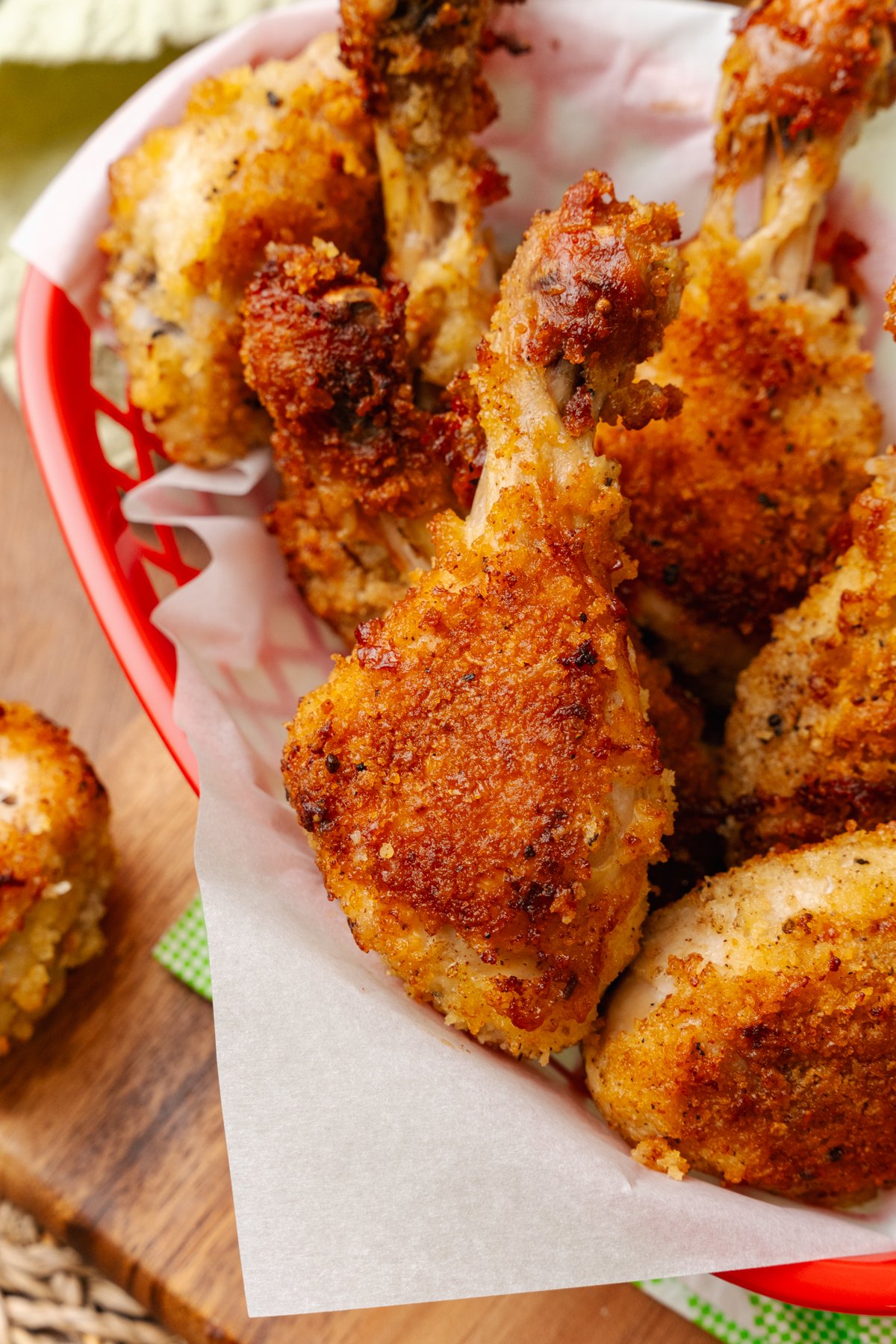 Fried chicken leg served on white parchment paper in a red basket.